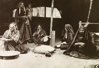 Palestinian bedouins at their tent. Four bedouin women, all dressed in long robes with headscarfs
