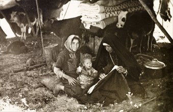 Bedouin women in their tent. Two bedouin women sit in the shade of their tent: one holding an