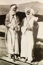 Two bedouin men on watch. Portrait of two bedouin men in traditional dress, one holding a rifle as