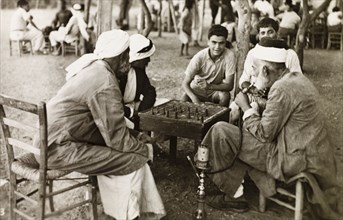 Socializing outside a cafe, Palestine. A group of Palestinian men sit around a table outside a