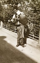 Lemonade seller, Palestine. A lemonade seller pours out a drink from a large jug strapped to his
