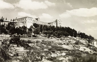 Salizian School', Nazareth. View of a large, majestic building situated atop a wooded hill,