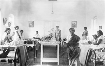 Maternity ward of a mission hospital, India. Two British nurses tend to Indian mothers and their