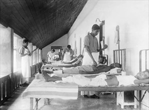 Male ward of a mission hospital, India. Indian medical officers tend to bedridden patients on the