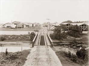 Railway tracks entering Port of Spain. A railway track crosses a river bridge on its approach to
