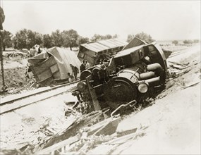 Derailed steam locomotive at Lydda. A steam locomotive lies upturned on a railway embankment,