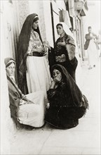 Four Arab women in Bethlehem. Four Arab women chat outside a doorway on a city street. All wear