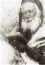 Portrait of an elderly Arab man. Portrait of an elderly Arab man reading from a book. British