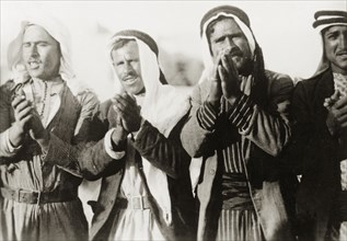Pilgrims at a Nebi Musa procession. Four Arab men clap their hands together as they take part in a
