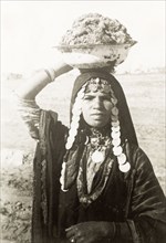 Portrait of a bedouin woman. Half-length portrait of a bedouin woman carrying a large bowl on her