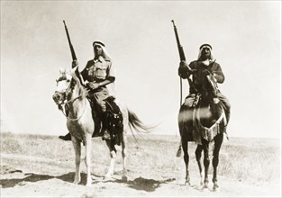 Desert police on patrol. Two mounted Arab police officers patrol the desert with rifles during the