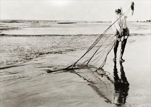 A Palestinian fisherman. An elderly Arab fisherman detangles his fishing net in shallow surf on a