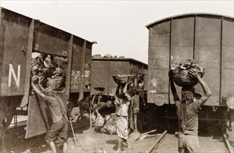 Coaling, the old fashioned way'. Indian porters collect baskets of coal from a railway freight car