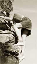 Climbing in Burragorang Valley. A European woman laughs as she struggles to climb a cliff face in