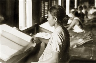 Sheets of latex in a rubber factory. A female factory worker examines sheets of latex at a rubber
