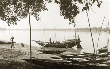 Unloading cargo on the Hooghly River. Men unload cargo from a small boat moored in the shallows of