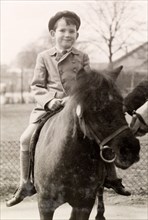 Pony ride at the zoo. A British boy named Tim smiles for the camera as he rides a pony during a