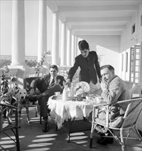 Tea on the veranda, India. Two European men take tea and breakfast on the pillared veranda of a