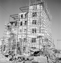 Construction of a six-storey building, Calcutta. A partially completed building is encased with