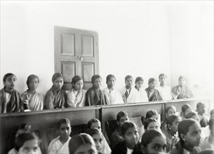 Students at girl's high school, Mysore. Rows of female Indian students sit on benches in a