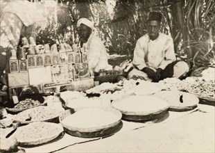 Food stall at Indian market. Two street traders sit in the shade of their covered market stall,
