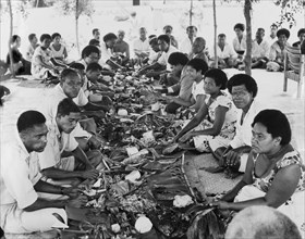 A Fijian 'magiti'. Two lines of diners sit cross-legged on the ground opposite each other during a