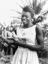 Antiguan woman with bananas. A young Antiguan woman smiles broadly as she displays a bunch of