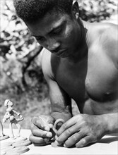 An Antiguan craftsman. A young Antiguan craftsman concentrates as he models small figurines out of