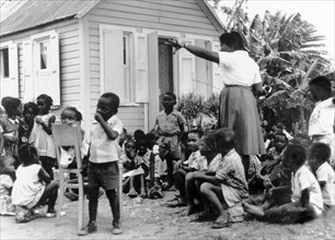 An outdoor classroom in Antigua. An Antiguan teacher oversees a group of schoolchildren outside a