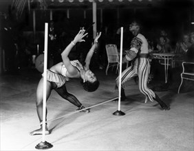 Limbo dancing at the Anchorage Hotel. A female limbo dancer bends over a limbo pole backwards
