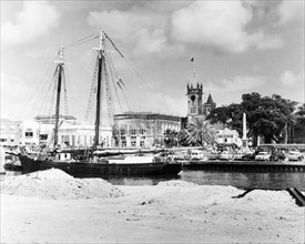 A ketch in the Careenage at Bridgetown. A ketch (twin-masted sail boat) sits at anchor in the