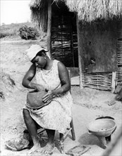 A potter in Monserrat. A woman fashions a clay pot by hand, resting it on her lap as she sits