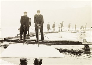 Ice cutters, Canada. A team of ice cutters stand on a pontoon bridge over Lake Ontario using ice