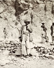 A Pashtun man on the Khyber Pass. Portrait of a turbaned Pashtun man posing by a dry stone wall on