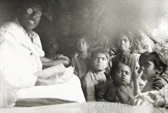 Reading to young children, India. A Methodist evangelist reads aloud from a book to a group of