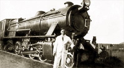 A narrow gauge steam train. Reverend Norman Sargant poses in front of a narrow gauge steam train as