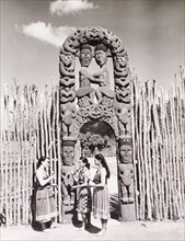 Women beneath a Maori arch. Three young Maori woman in traditional dress chat beneath an ornate