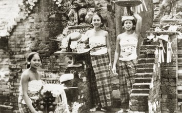 Balinese women posing on temple steps. Three young Balinese women wearing traditional 'kain sarung'