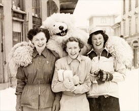 Posing with a polar bear, Switzerland. Three female tourists pose with a performer in polar bear