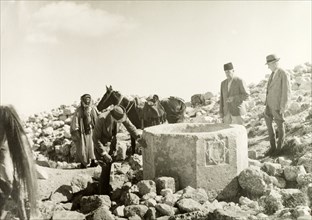Stone well in the desert. William Ryder McGeagh, District Commissioner in Jerusalem, examines a