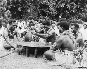 Performing a 'sevusevu' ceremony. Five Fijian men sit in a circle around a wooden 'tanoa' as they