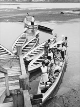 At a wooden jetty on the Nasilai River. A motorised canoe full of people carrying goods to market