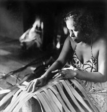 Weaving pandanus leaves. A Tahitian woman concentrates as she weaves pandunas leaves by hand.