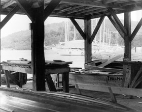 A boat-building workshop at English Harbour. Wooden beams support the roof of a boat-building