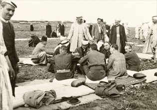 Recruitment meeting at Al Faluja. British colonial and military officers sit on padded mats and