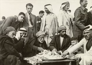 Arab meal at a military recruitment meeting. A group of Arab men wearing turbans and 'keffiyehs'