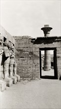 Temple of Ramesses III at Karnak. A line of eroded stone statues guard a courtyard in the Temple of