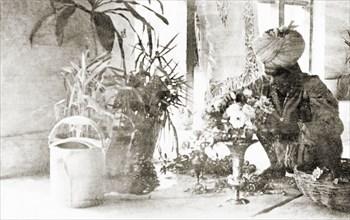 A servant tending to houseplants. A gardener arranges a vase of flowers at the Police Training