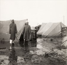 Flood at an Indian Police camp. Two Indian men stand in front of flooded tents at the James