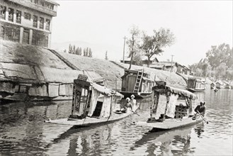 Water taxis on a Srinagar canal. Two water taxis travel along Lake Dal past a several moored